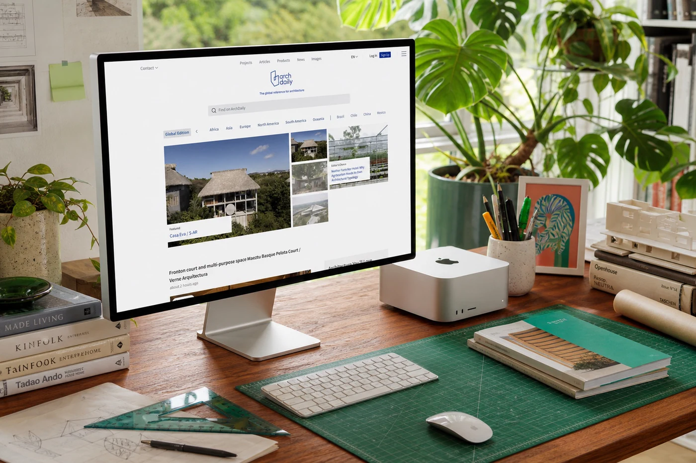ArchDaily homepage displayed on a Studio Display in a warm workspace